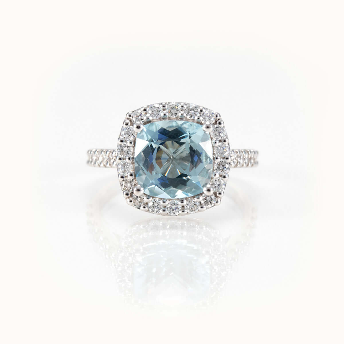 Elegant aquamarine ring featuring a cushion-cut gemstone and diamond halo set in 14 kt white gold.