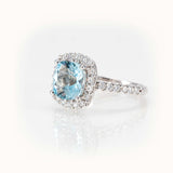 Elegant aquamarine ring with diamond halo, featuring a cushion-cut gemstone in a white gold setting.