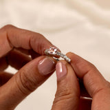 Elegant east-west pink morganite and diamond half-eternity ring held in hand, showcasing its sparkling beauty.