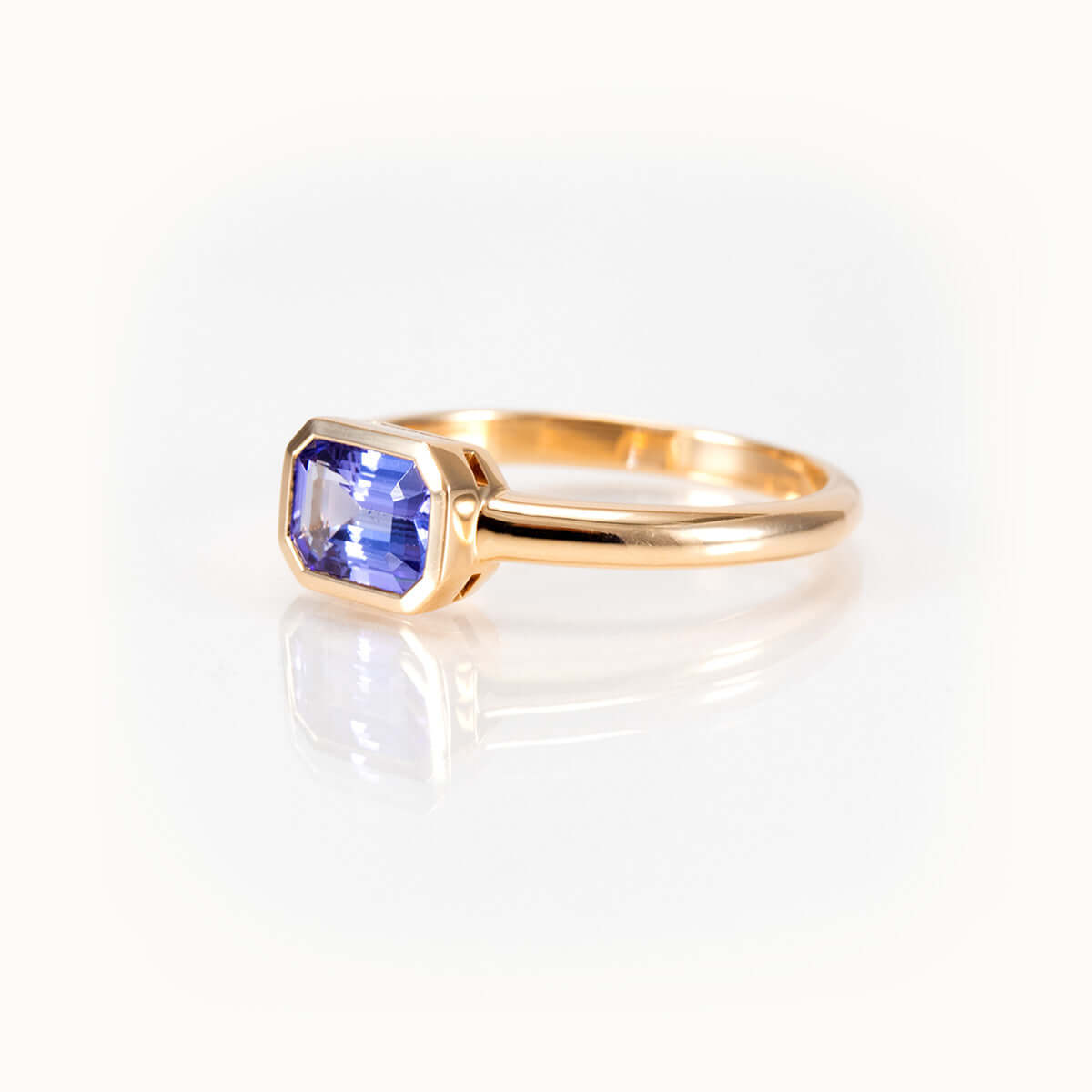 Elegant light purple tanzanite ring in 14 kt yellow gold bezel setting, showcasing a unique east-west orientation.