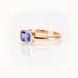 Elegant light purple tanzanite ring in 14 kt yellow gold bezel setting, showcasing a unique east-west orientation.