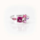Elegant bespoke design ring featuring a cushion-cut pinkish purple garnet with sapphire side stones in 14kt white gold.