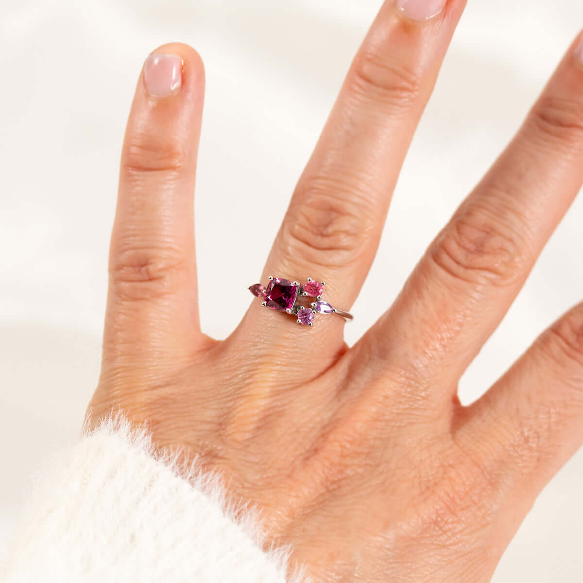 Elegant pinkish purple garnet ring with sapphire side stones, showcasing timeless sophistication in a hand display.