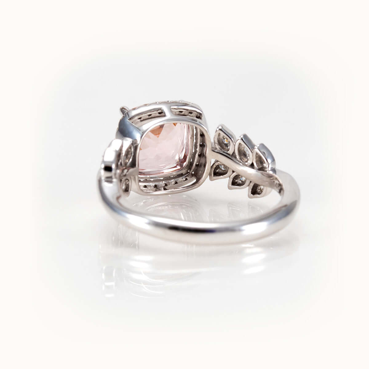 Elegant pink morganite ring with diamond halo and leaf-inspired band in white 14K gold.