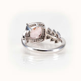 Elegant pink morganite ring with diamond halo and leaf-inspired band in white 14K gold.