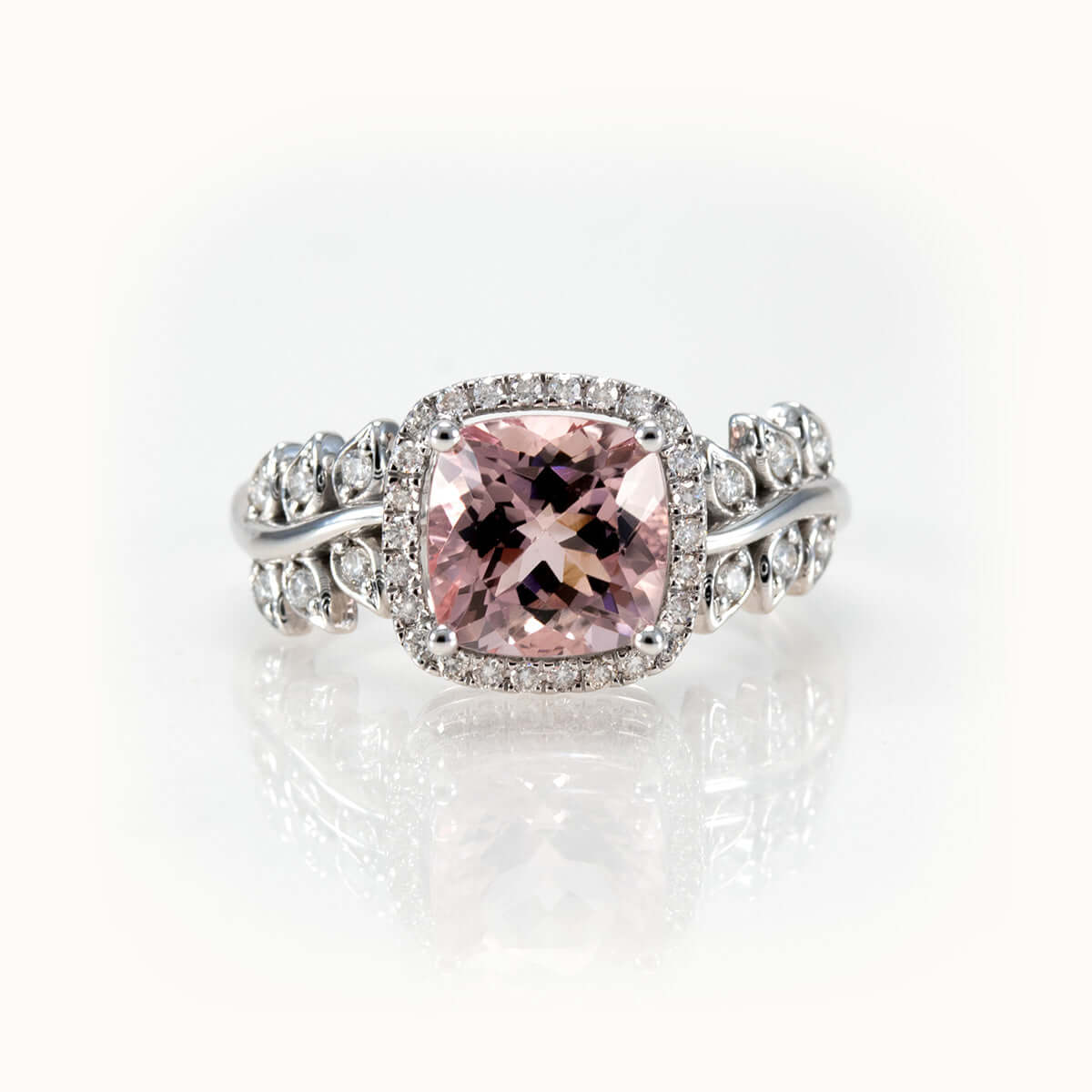 Pink morganite ring in 14K gold with diamond halo and leaf-inspired band, showcasing timeless elegance and bespoke design.