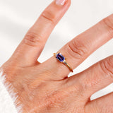 Light blueish-purple tanzanite east-west ring in 14K yellow gold worn on a hand.