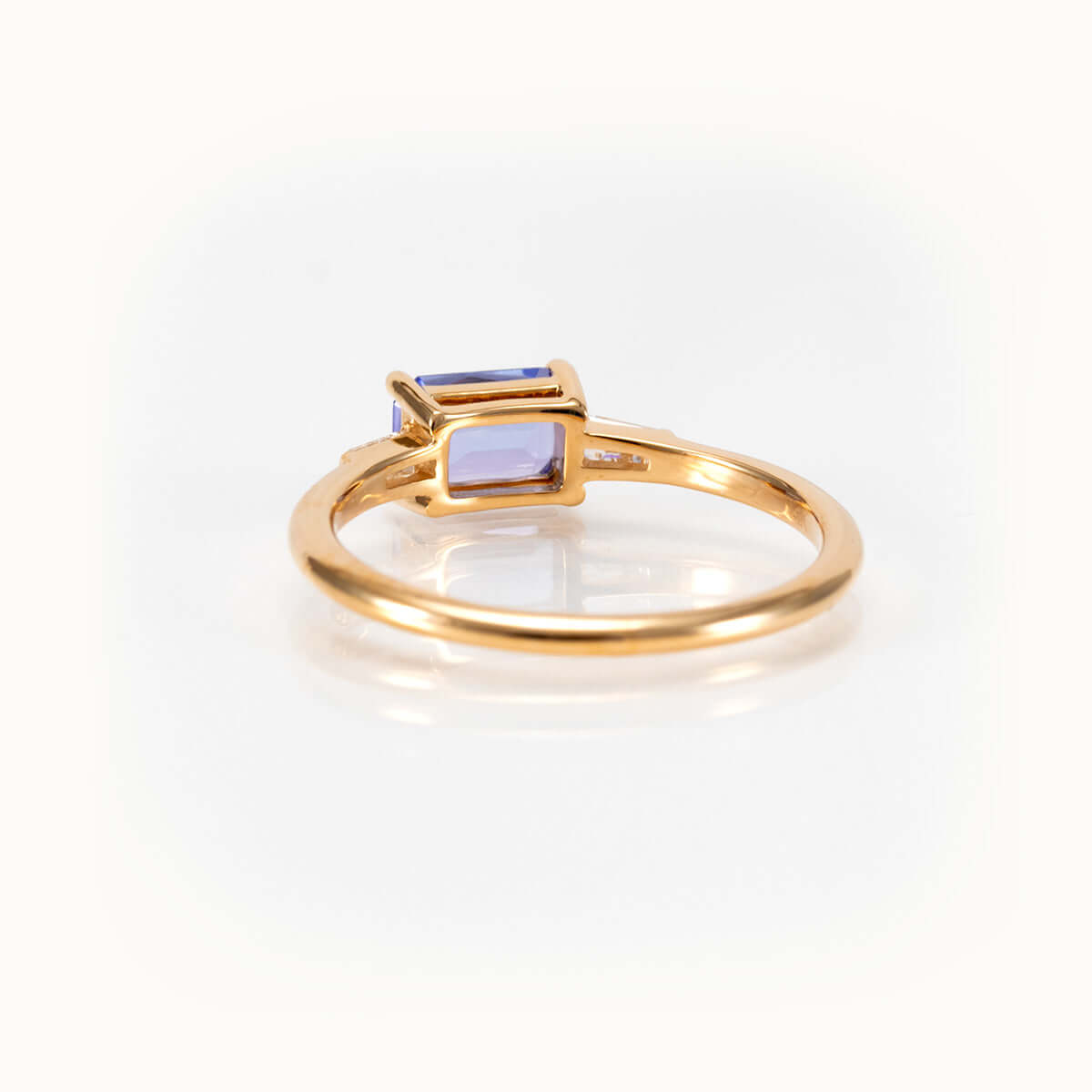 Light blueish-purple tanzanite east-west ring in 14K yellow gold, showcasing a bespoke and elegant gemstone design.