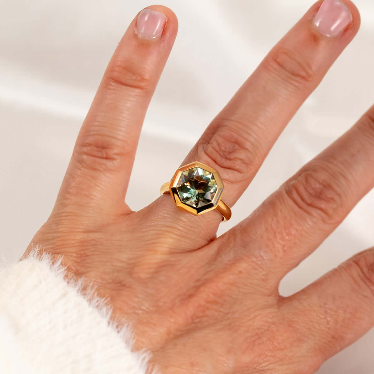 Hand wearing an octagon-cut prasiolite ring in 14K yellow gold, showcasing its unique bespoke gemstone design.